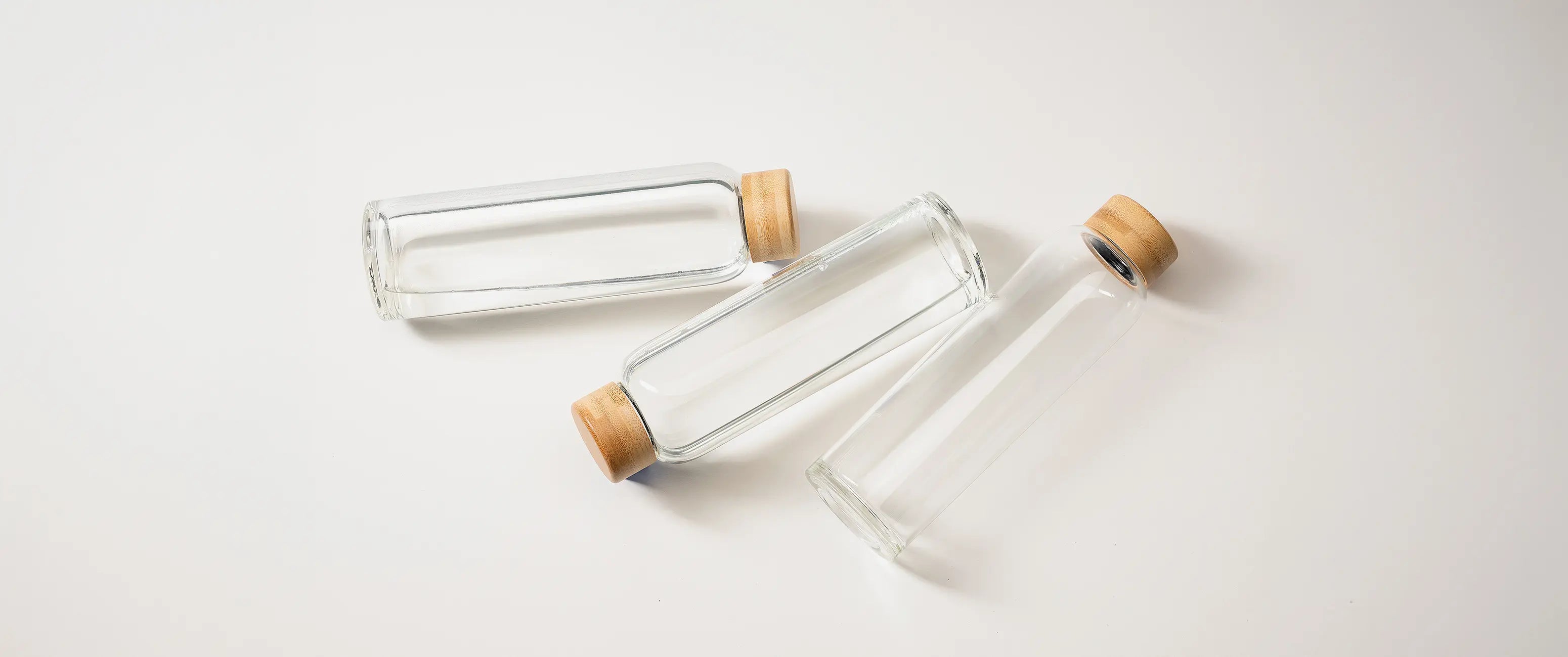 Drei BELAMY Glasflaschen aus Borosilikatglas mit Bambusdeckeln liegen nebeneinander
